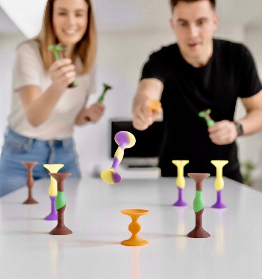 Zwei lachende Menschen, die an einem Tisch SiliDarts spielen.